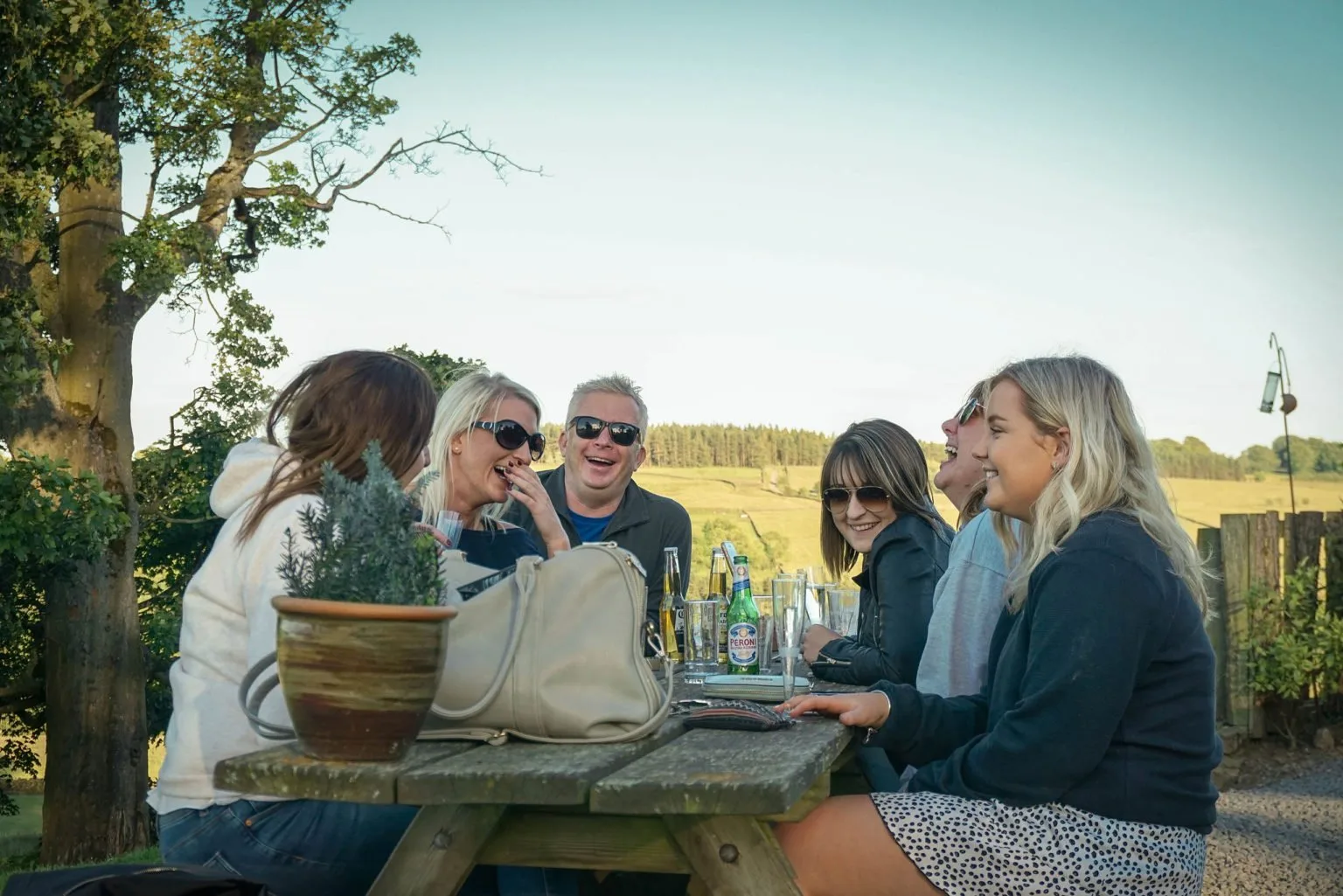 Friends laughing around an outdoor picnic table at the Bivouac