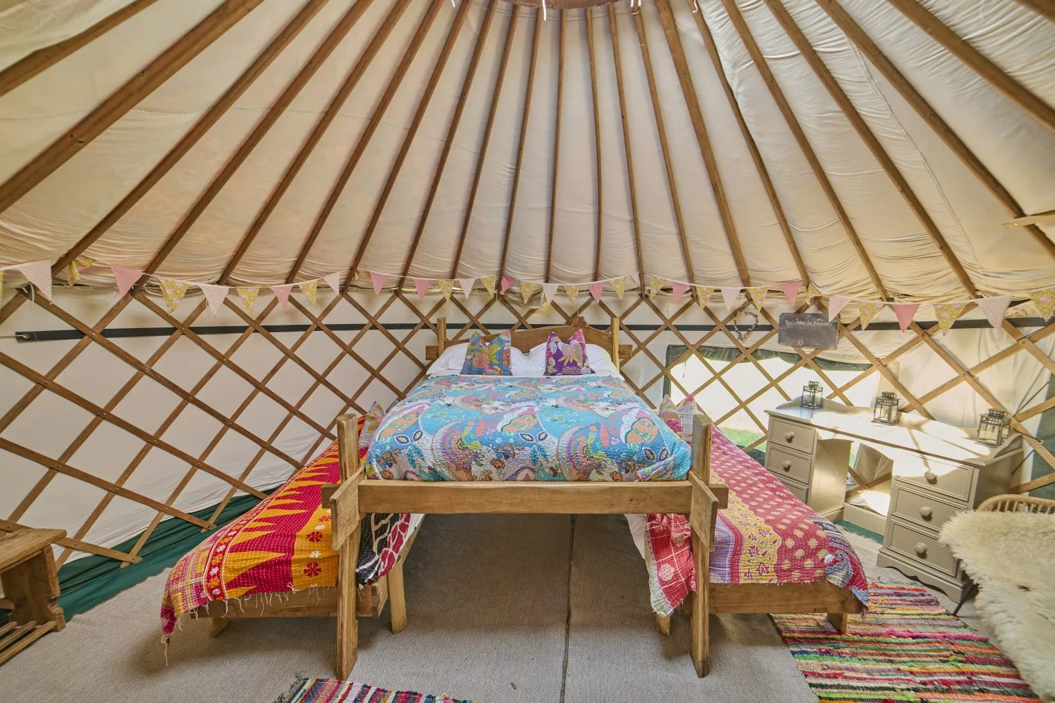 A bed made up under the roof lattice of a Meadow Yurt