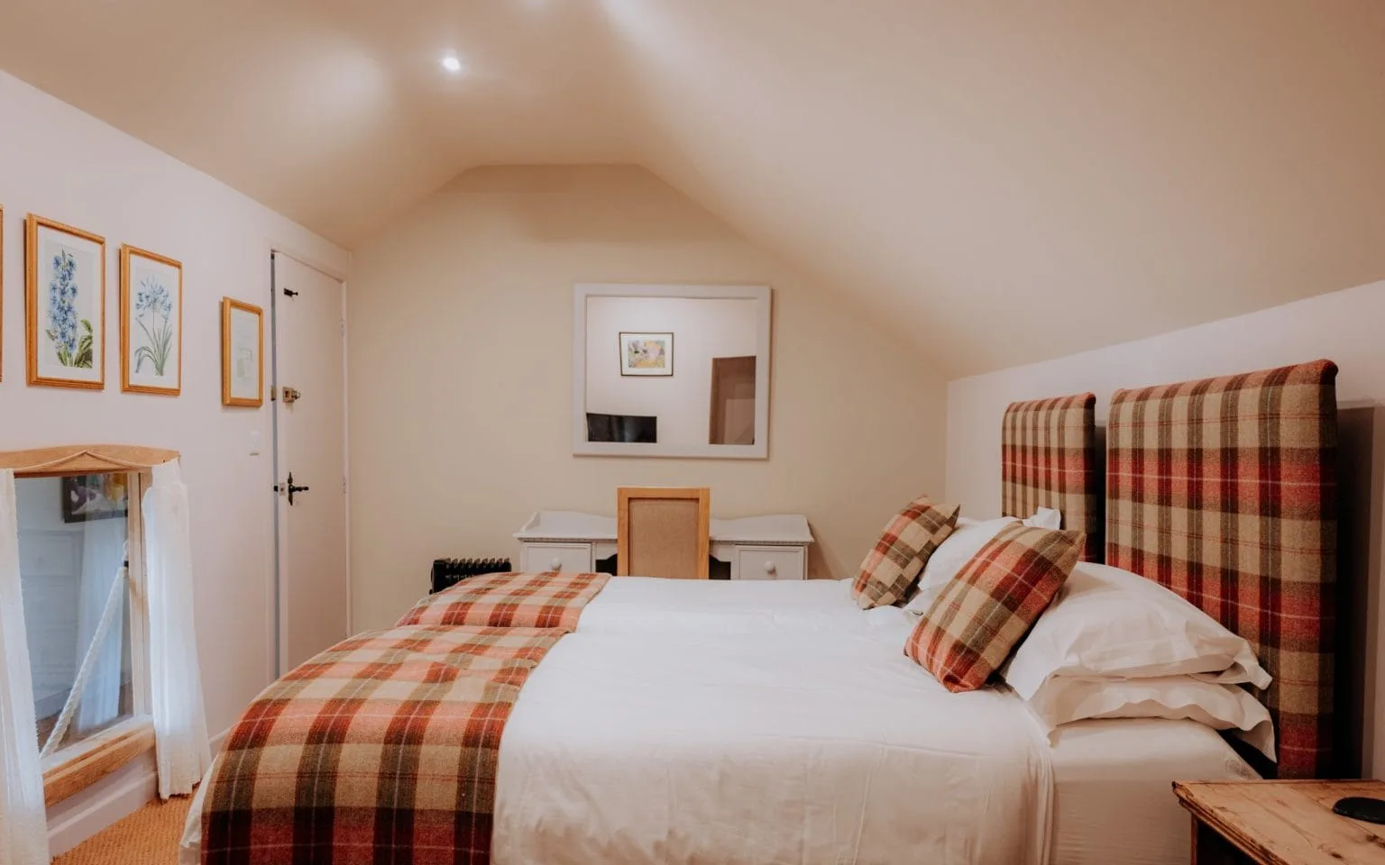 The bedroom of The Loft, with tartan headboards and a plaid throw