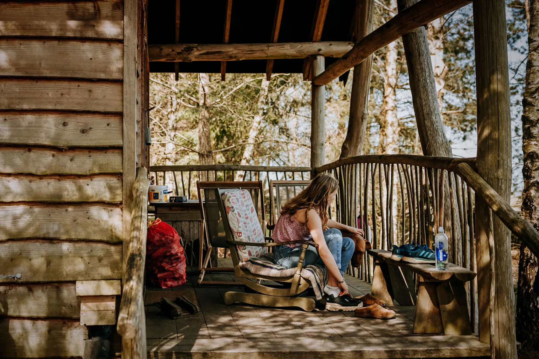 A guest relaxing in a chair on the veranda of a Tree Lodge